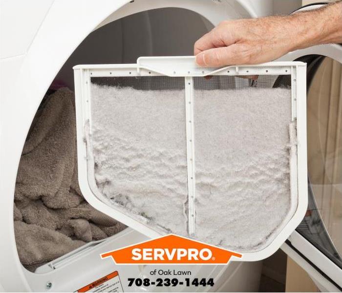 A person removes lint from a dryer lint trap.